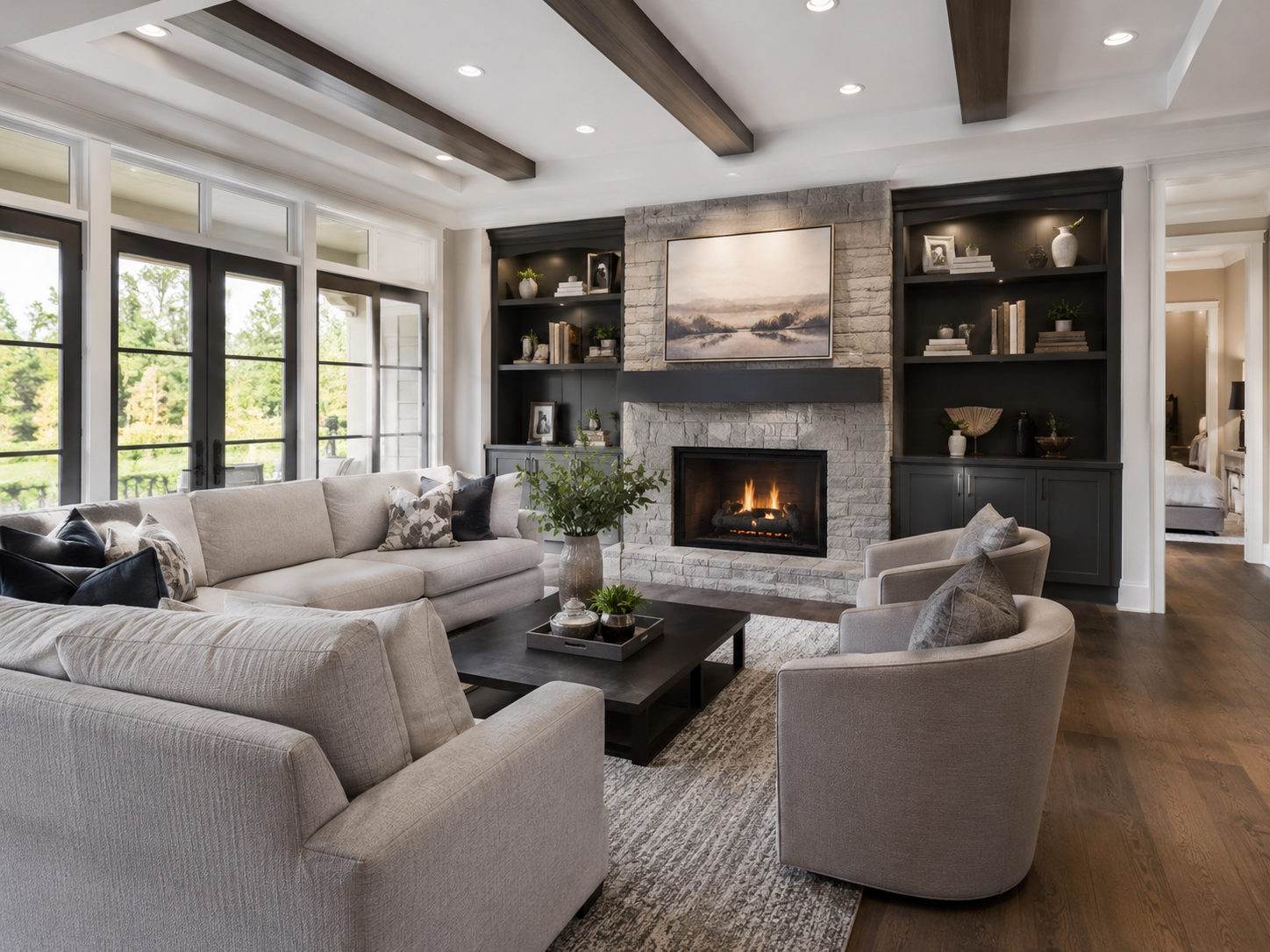 Great room with stone fireplace, built-in shelving, and exposed beam ceiling
